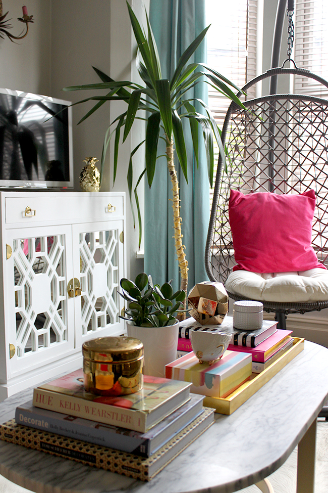 coffee table vignette with hanging chair in background and vintage tv cabinet