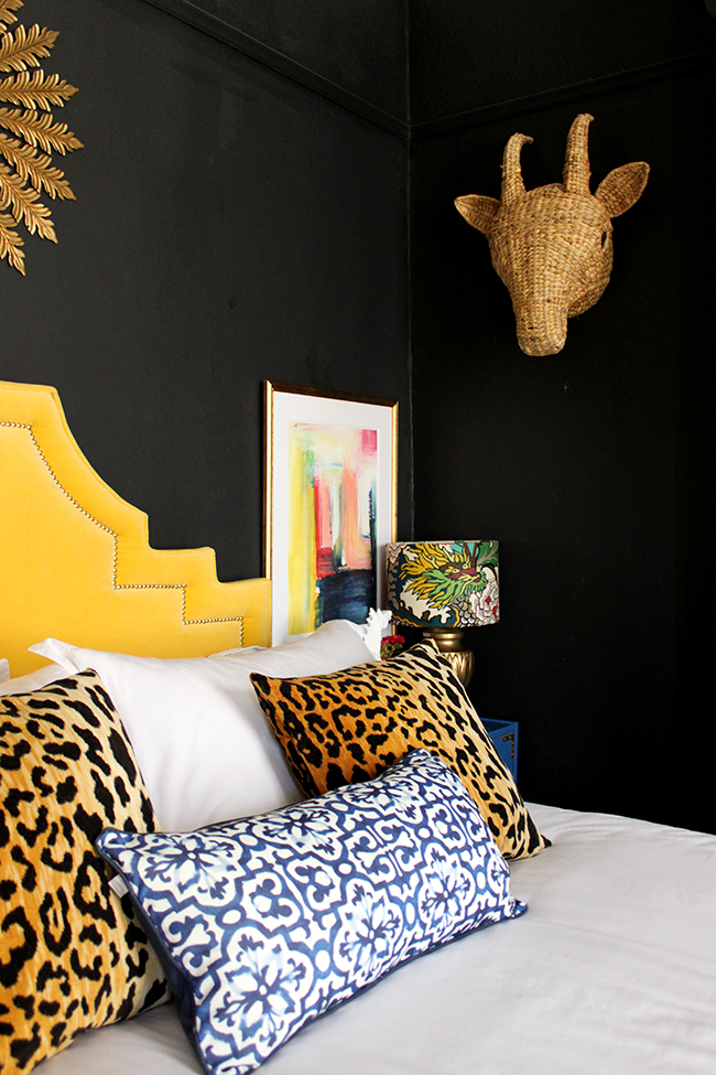 Swoon Worthy bedroom - yellow headboard, abstract art, leopard cushions, black walls