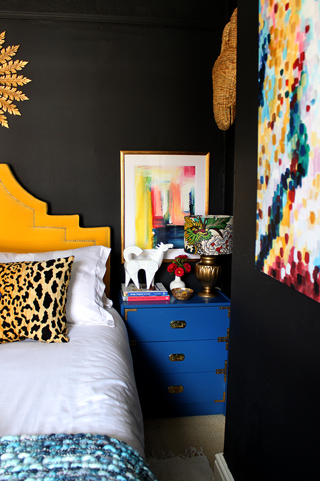 Swoon Worthy bedroom - blue ikea rast hacks, colourful abstract art, yellow headboard, black walls