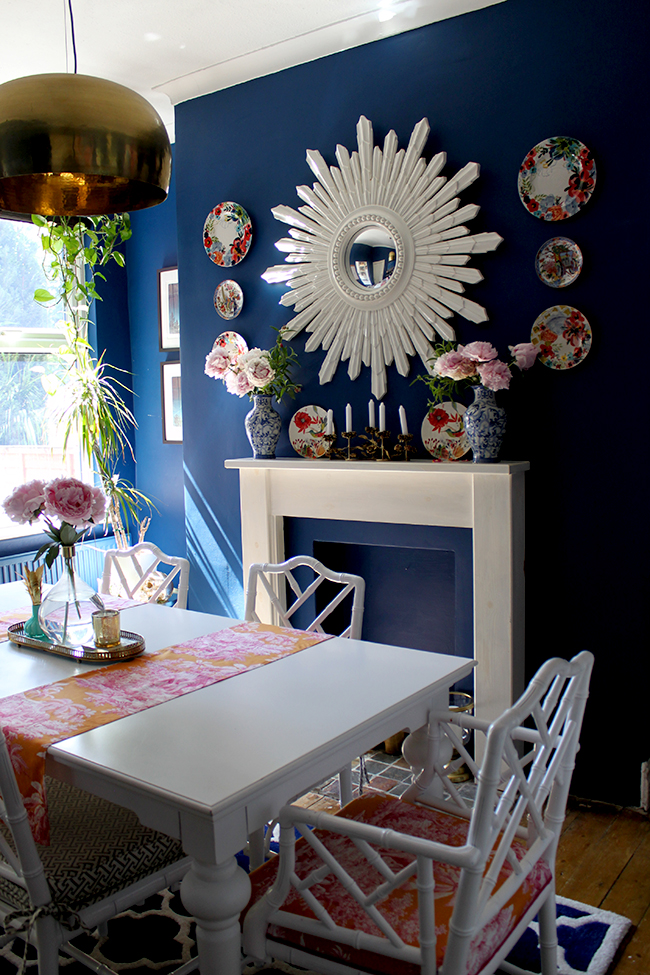 Swoon Worthy dark blue dining room with white furniture and starburst mirror