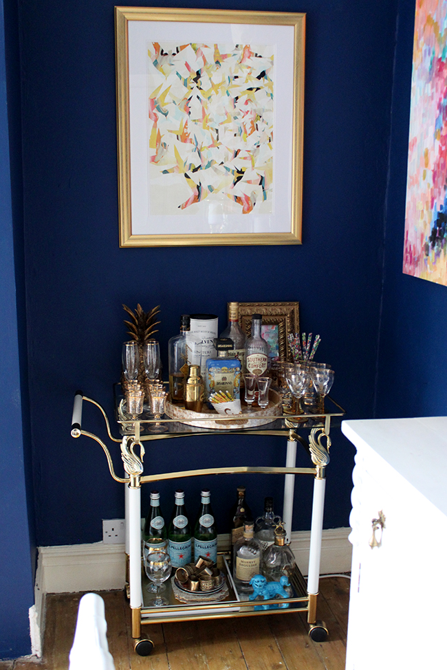 brass barcart against dark blue wall - see more at www.swoonworthy.org