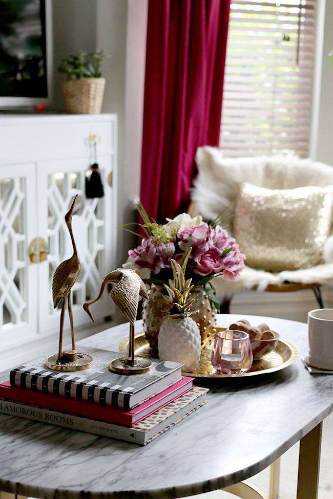 coffee table styling - brass cranes, marble coffee table, pink flowers, white and gold pineapple, brass tray, pink candle