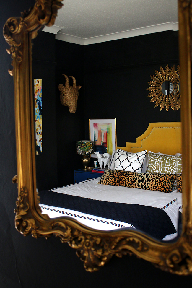 black bedroom with colourful accents, yellow headboard, sunburst mirror - see more on www.swoonworthy.org