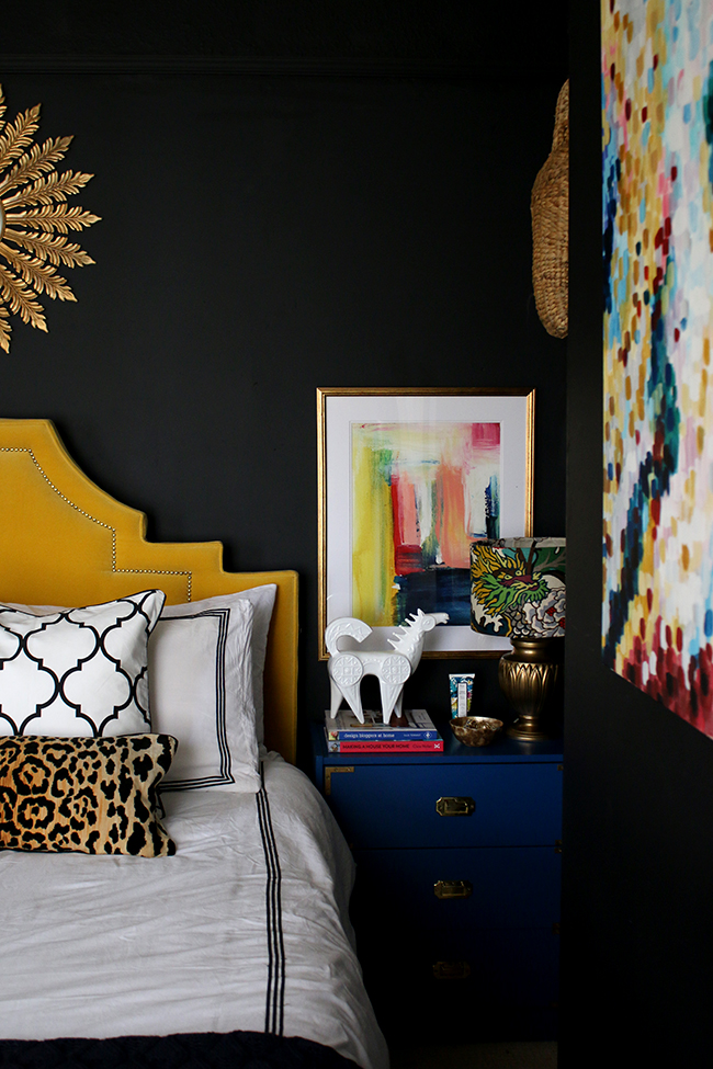 black bedroom with colourful accents, yellow headboard, sunburst mirror - see more on www.swoonworthy.org