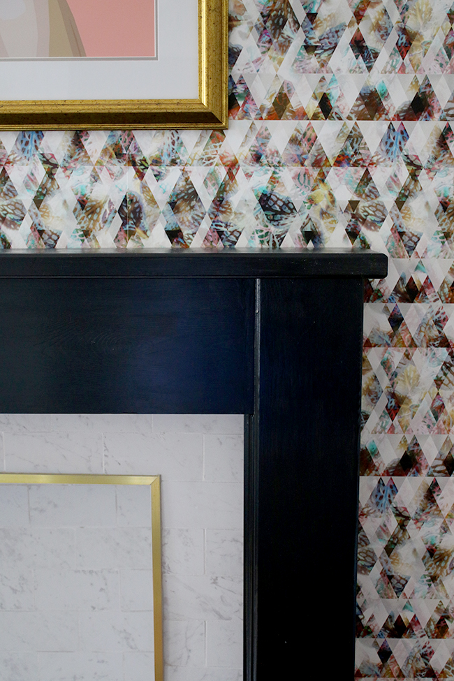 marble tile fireplace with brass trim and black hearth with graphic wallpaper