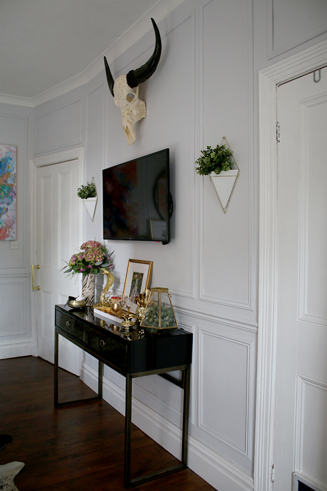 wall paneling, black console table with TV, wall planters, skull - see more on www.swoonworthy.org