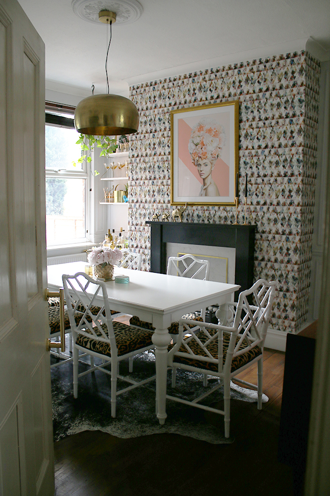 Eclectic glam living room with graphic feature wallpaper, leopard print chairs, black and marble fireplace, gold light fixture - see more on www.swoonworthy.org