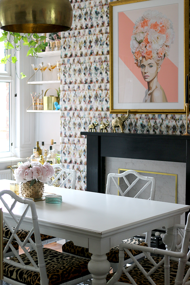 Eclectic glam living room with graphic feature wallpaper, leopard print chairs, black and marble fireplace, gold light fixture - see more on www.swoonworthy.org