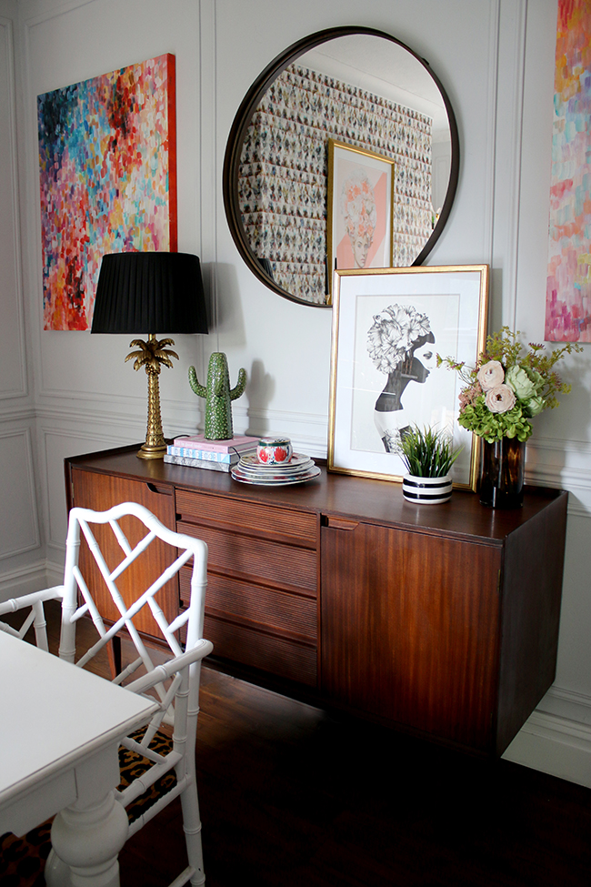 mid-century sideboard with palm tree lamp, round mirror and abstract art - see more on www.swoonworthy.org