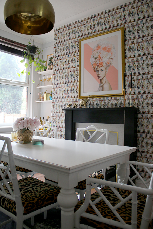 Eclectic glam living room with graphic feature wallpaper, leopard print chairs, black and marble fireplace, gold light fixture - see more on www.swoonworthy.org