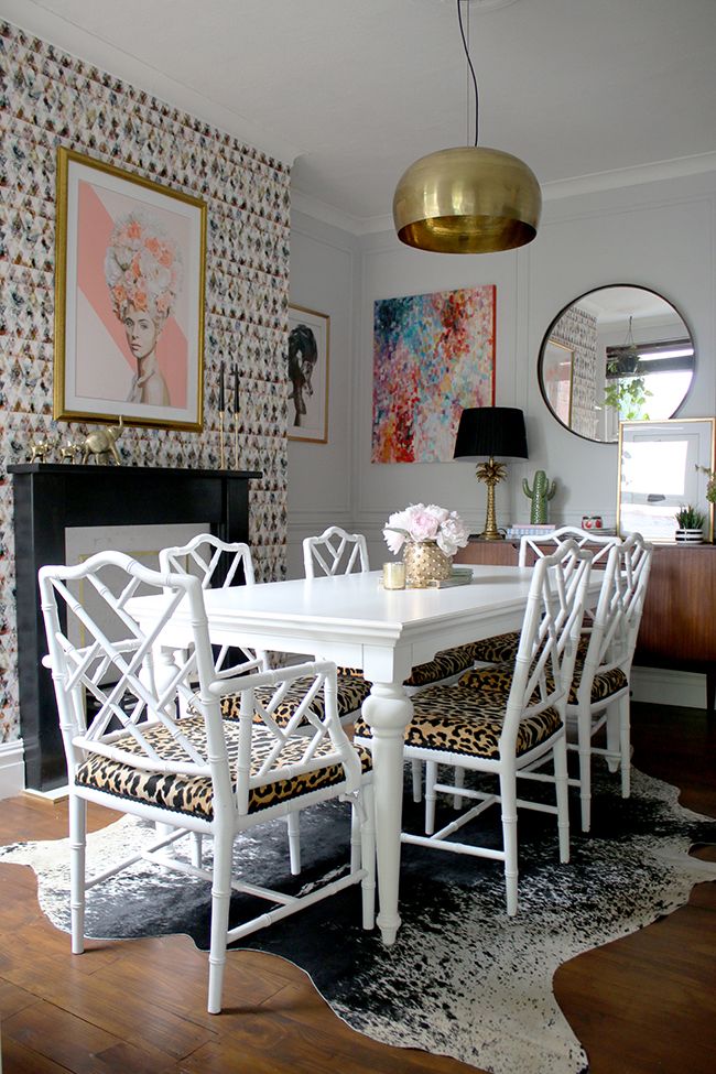 Eclectic glam living room with graphic feature wallpaper, leopard print chairs, black and marble fireplace, gold light fixture - see more on www.swoonworthy.org