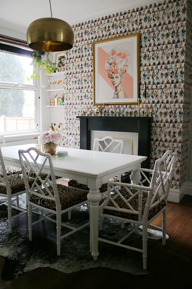 Eclectic glam living room with graphic feature wallpaper, leopard print chairs, black and marble fireplace, gold light fixture - see more on www.swoonworthy.org