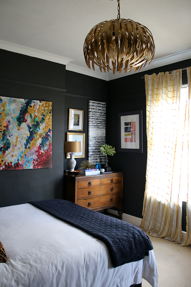 black bedroom with vintage dresser and gallery wall, yellow curtains - see more on www.swoonworthy.org