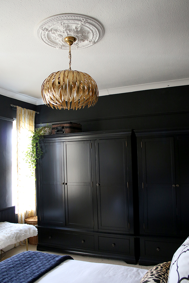 black bedroom wardrobes with gold light fixture and ornate gold mirror - see more on www.swoonworthy.org