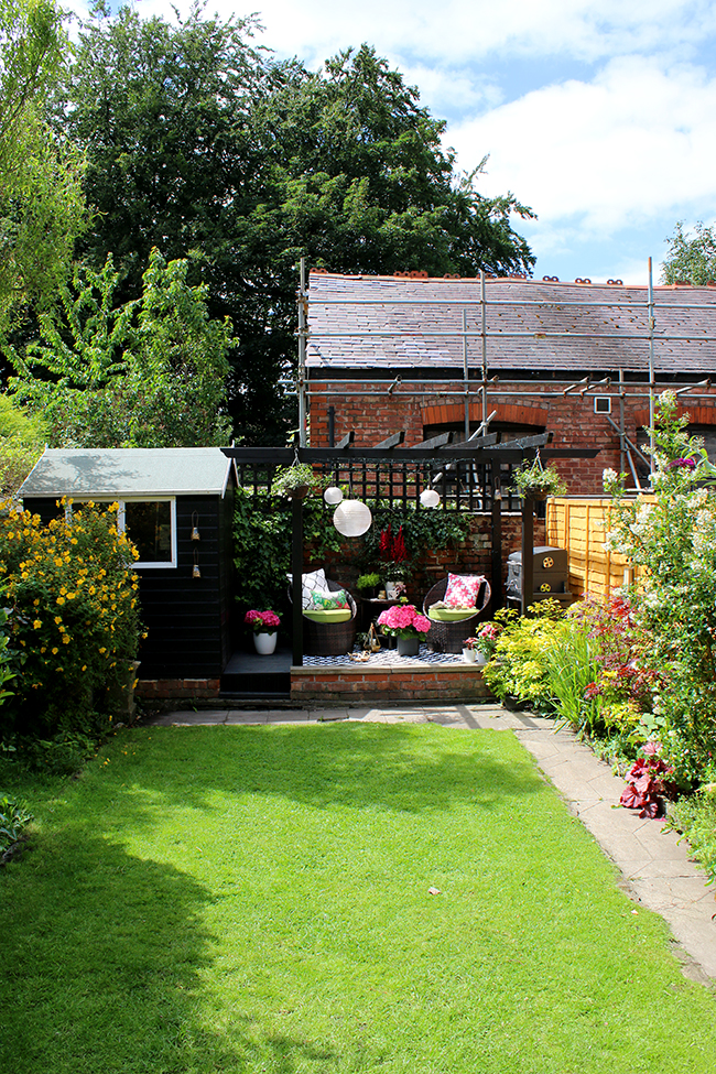 English garden with black pergola and mature plants