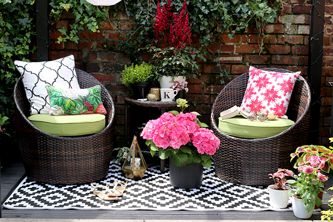 Black Patio with brick wall and black and white outdoor rug, green and pink accessories