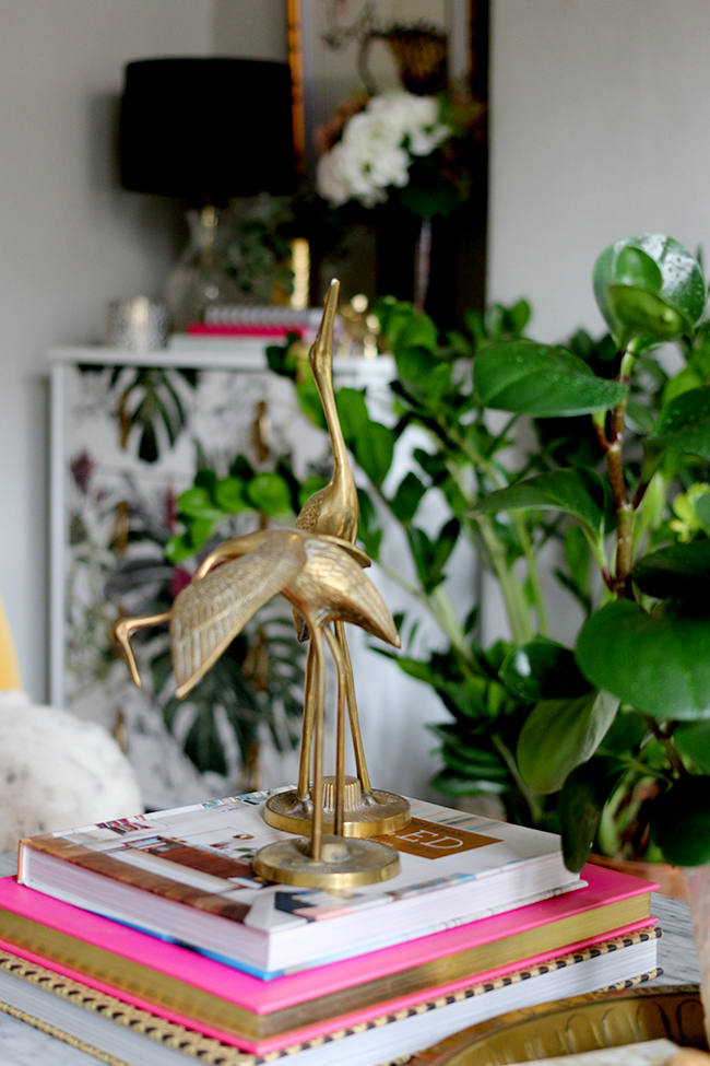 coffee table vignette with brass cranes and houseplants