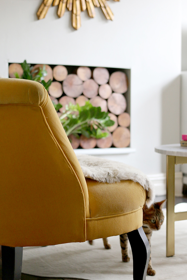 yellow sofa in living room with decorative logs in fireplace