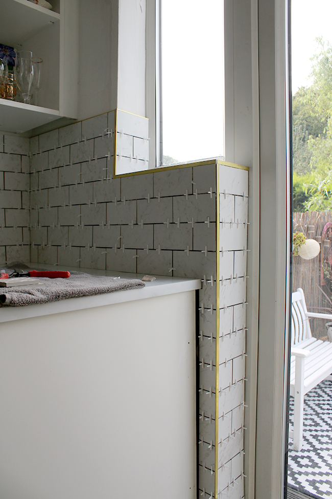 Updating our interiors with marble effect kitchen tiles and brass trim.