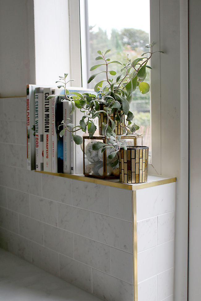 Marble effect porcelain tiles with brass trim work along windowsill