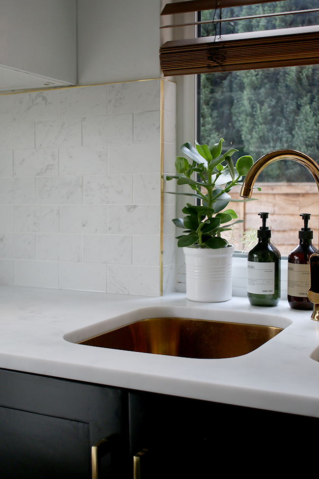 gold sink and tap with white marble tiles and brass trim