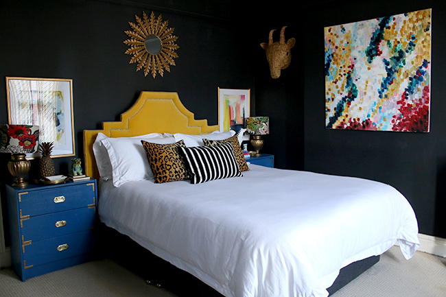 black bedroom with blue nightstand and yellow headboard