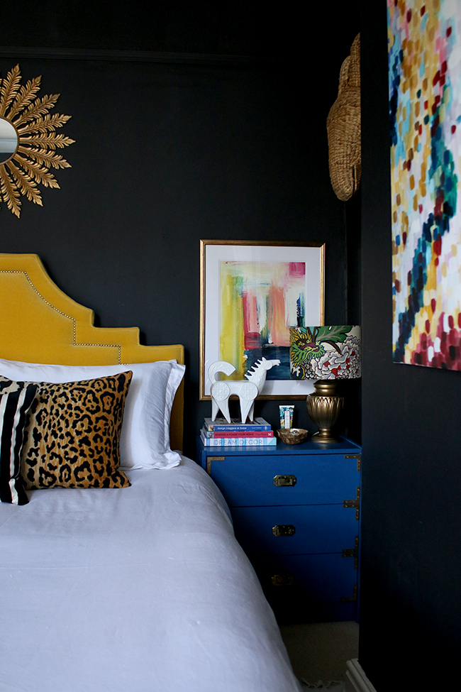 black bedroom with blue nightstand and yellow headboard