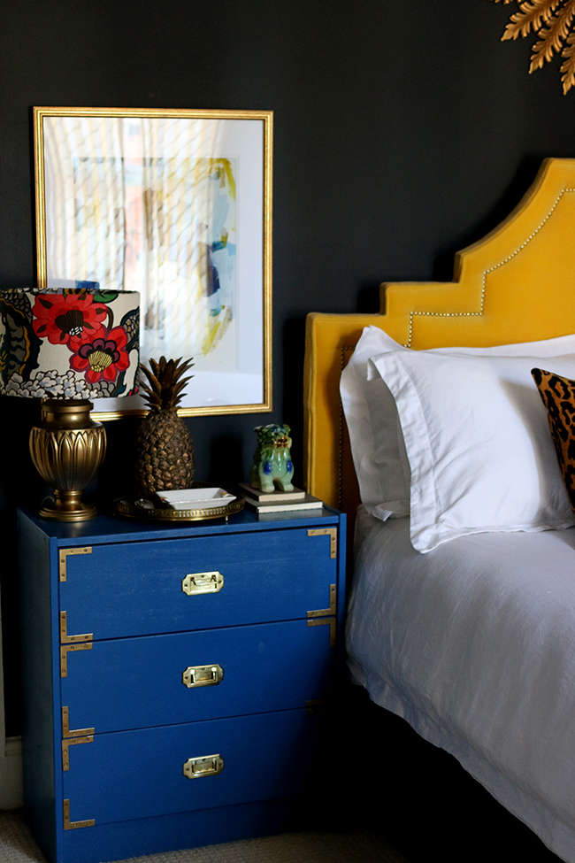 black bedroom with blue nightstand and yellow headboard