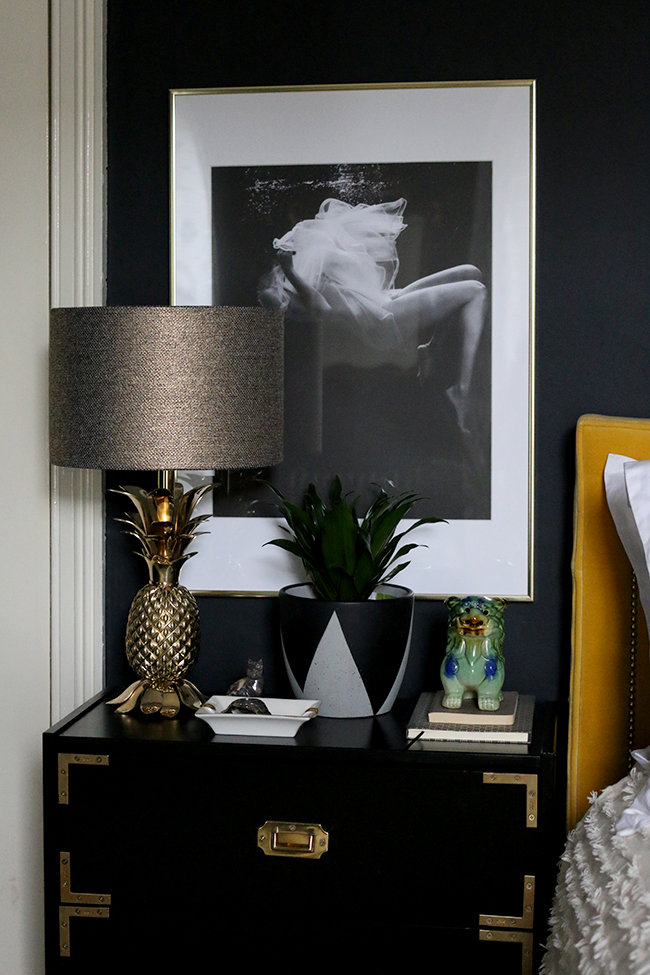 black campaign style nightstand with gold pineapple lamp