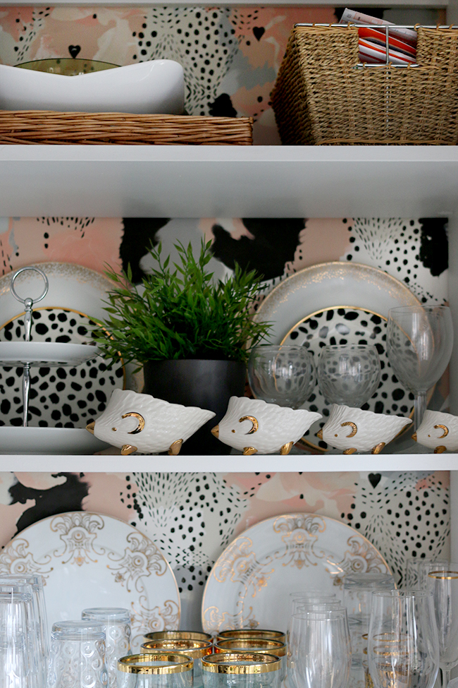 open shelf styling with peach and spotty wallpaper and gold accents