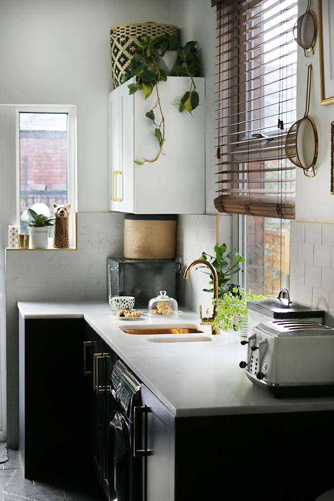 kitchen with black cupboards with white open shelving, marble tiles, gold sink and gold tap