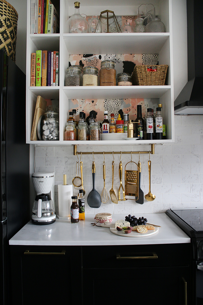 black and white kitchen with marble tiles and gold hanging utensils