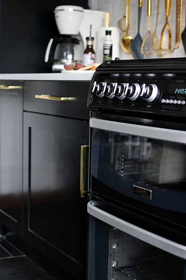 Black oven from AO.com with black cupboards and gold hardware in kitchen