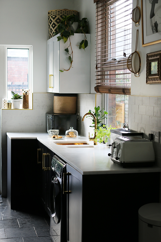 kitchen with black cupboards with white open shelving, marble tiles, gold sink and gold tap