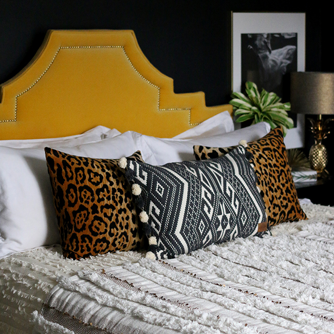 black bedroom with leopard print cushion, yellow headboard and moroccan wedding blanket throw