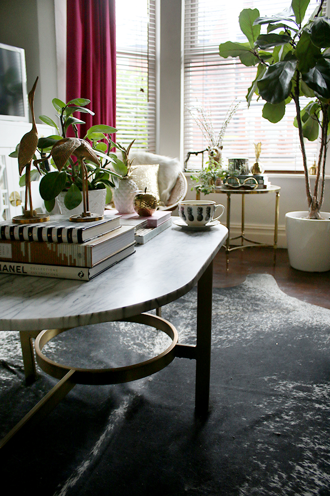 black and white cowhide speckled rug in living room with marble and gold coffee table