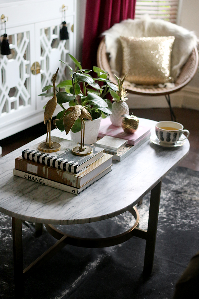 marble and gold coffee table on black speckled cowhide rug with vintage brass - coffee table styling