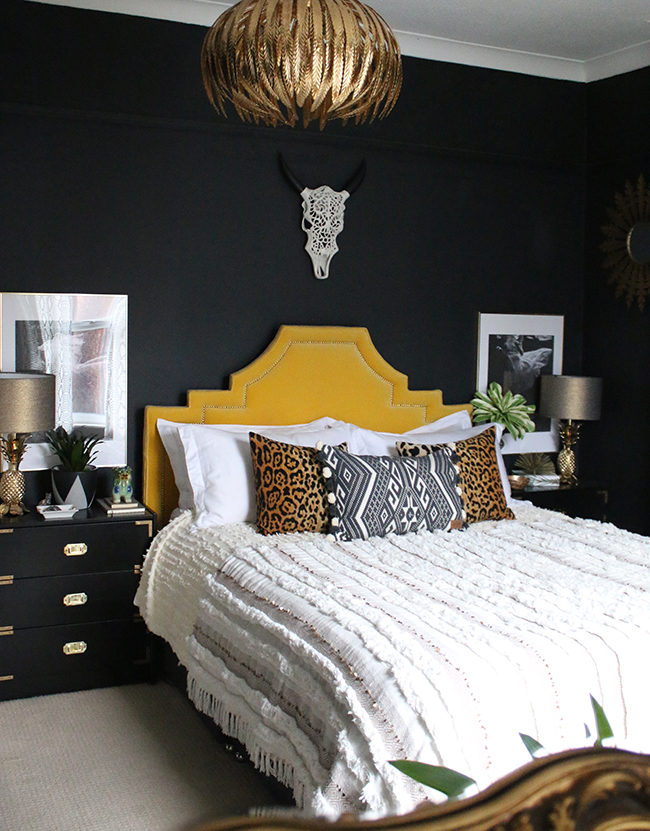 boho glam bedroom with yellow headboard and black walls 