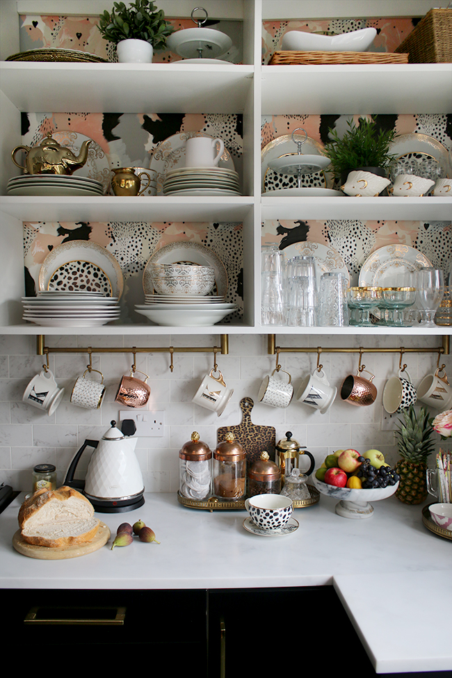 open shelving in kitchen with wallpaper and gold and copper accents