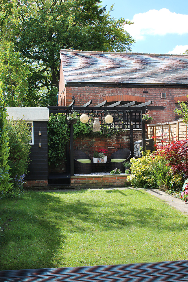 Edwardian home garden with black pergola and shed and DIY bamboo solar lights