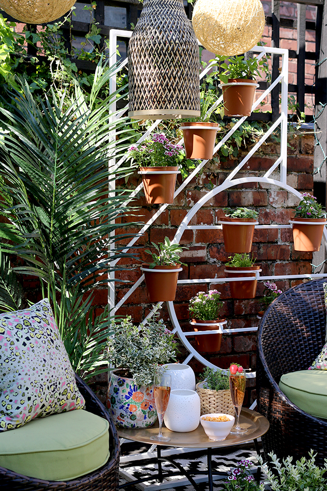 Boho garden pergola in green and pink with gold accents and white West Elm plant stand