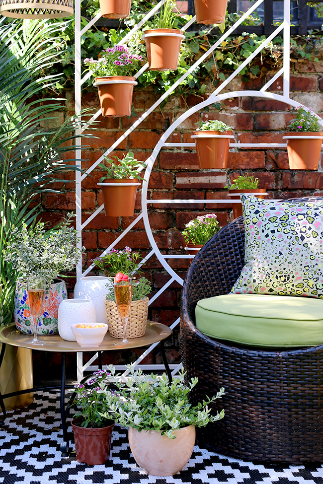 Boho garden pergola in green and pink with gold accents and white West Elm plant stand