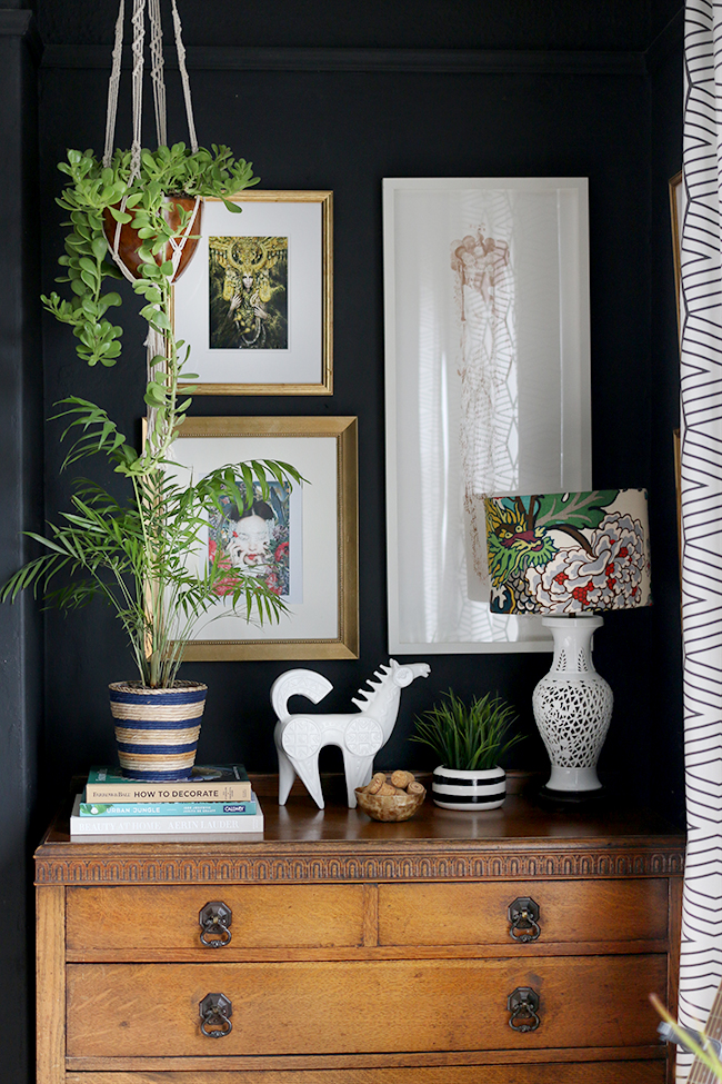 black boho glam bedroom with vintage dresser and plants