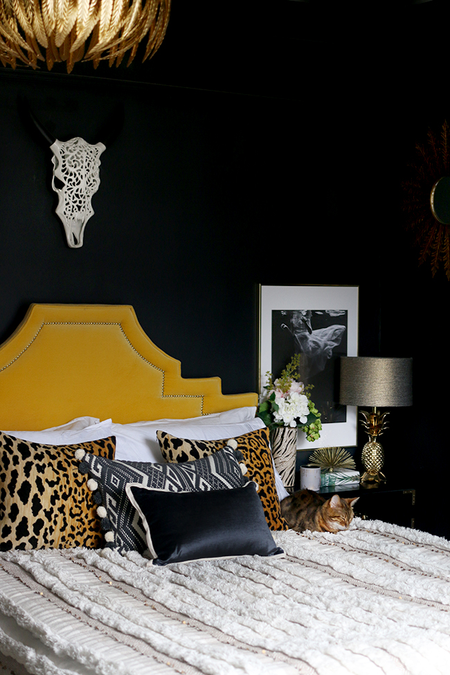 black bedroom with yellow velvet headboard leopard print cushions and gold pineapple lamp