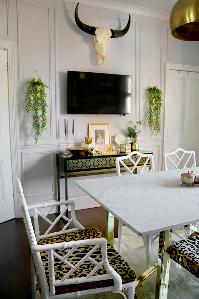 Farrow and Ball Blackened dining room with marble table and brass base with chippendale chairs in white and leopard print