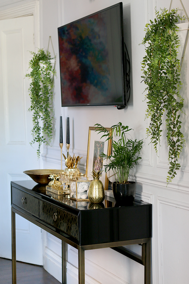 grey dining room with black and gold console and TV on wall