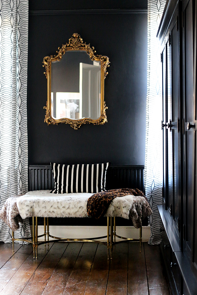 black bedroom with gold mirror and dark wood floors