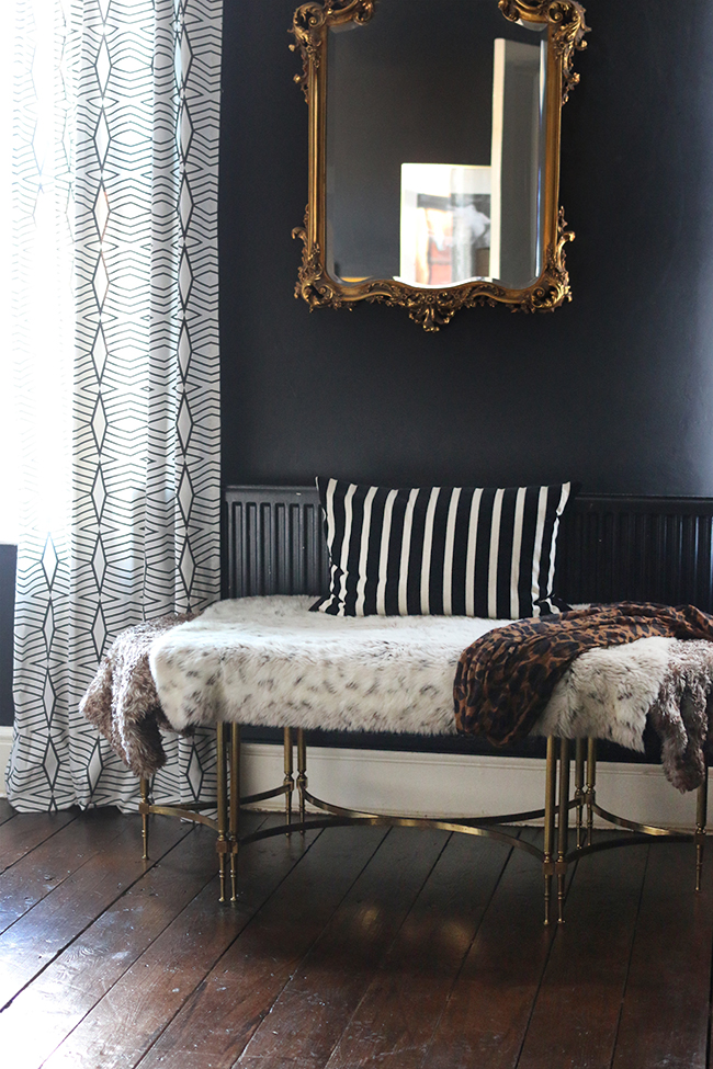 black bedroom with gold mirror and dark wood floors