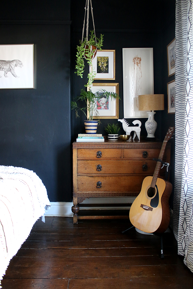 black bedroom with vintage chest of drawers and gallery wall