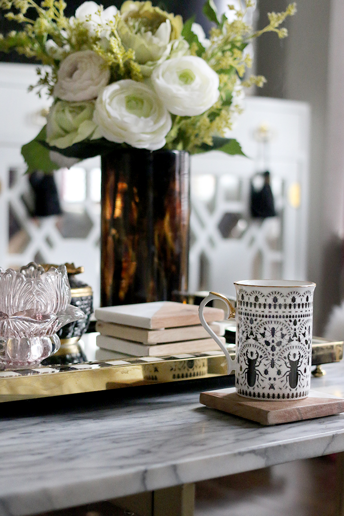 cup of coffee on marble coffee table with flowers